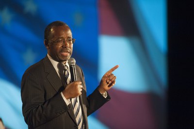 A professsional speaker talking into the microphone on stage.
