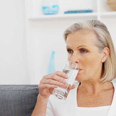 Older woman drinking glass of water.