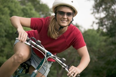 A woman wearing a helmet on a bicycle.