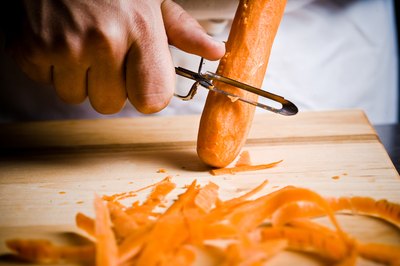 A cook peels a carrot.