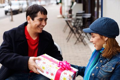 A woman gives a smiling man a present.