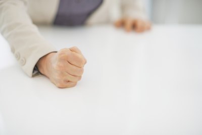 A close-up of a businesswoman slamming her fist on the desk.