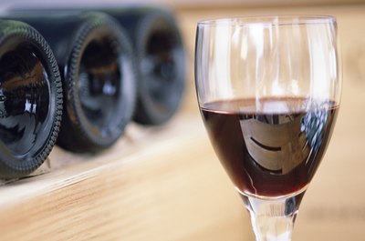 A glass of red wine with bottles in background
