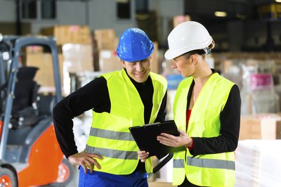 two workers in safety gear looking at clipboard