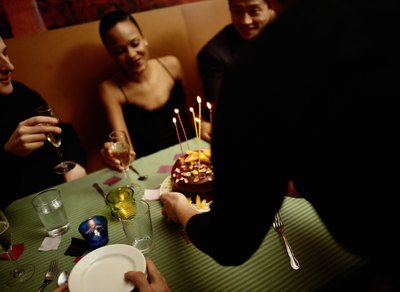 waiter bringing birthday dessert to table