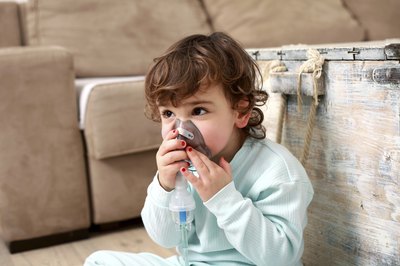 A small child uses an inhaler mask.