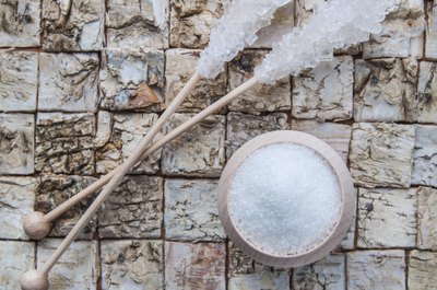 Small bowl of aspartame beside two pieces of rock candy.
