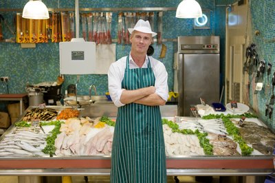 Fish market owner standing in front of display counter.