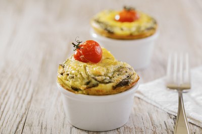 A spinach omelet in a ramekin with a cherry tomato on top.
