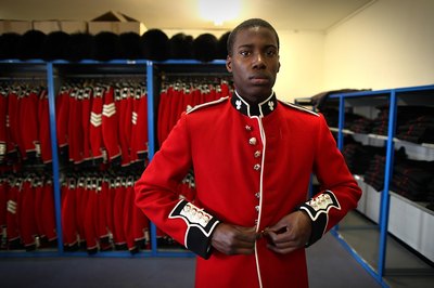 An Irish soldier puts on a red jacket for a St. Patrick's Day parade.