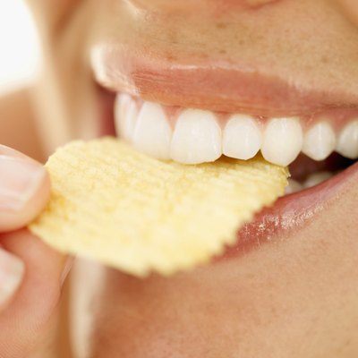 A close-up of a woman eating a potato chip.