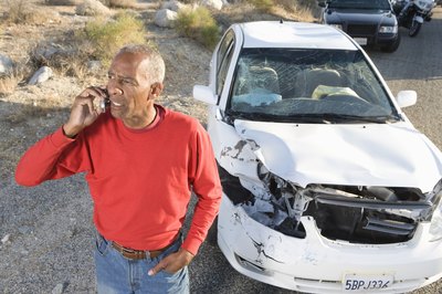 Man on phone with damaged car.