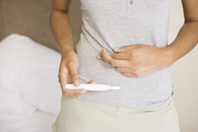 woman with nausea holding pregnancy test