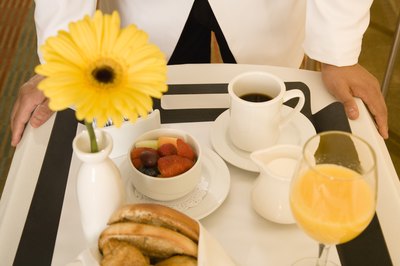 A waiter serving a continental breakfast on a tray.