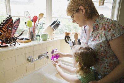 Mother helping daughter wash hands