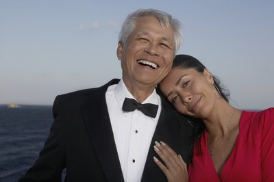 A couple in formal wear on the deck overlooking the water.