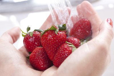 A woman washes fresh strawberries.