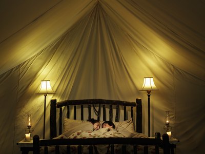 A young couple in bed with lit candles.