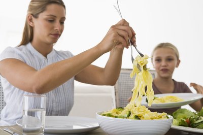 woman serving pasta to child
