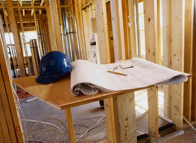 A blueprint sits on a work bench next to a hard hat.