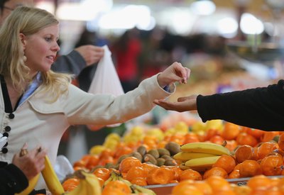 A woman purchases fruit from a vender at a market.