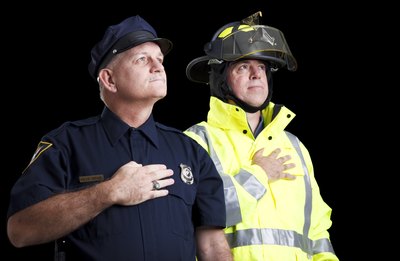 Two firemen hold their hands over their hearts while singing the U.S. national anthem