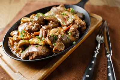 Liver baked with mushrooms and herbs in a cast iron pan.