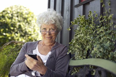 A woman uses her smart phone in the backyard.
