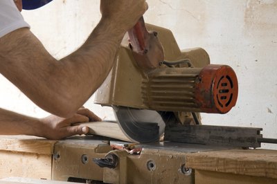 A workman uses a table saw to cut a wood board