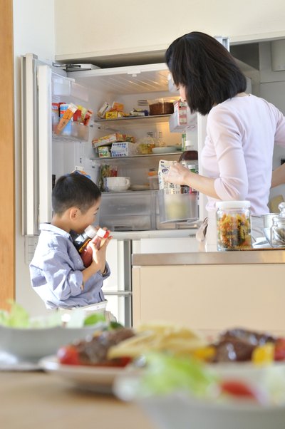 Mother and son putting groceries in fridge