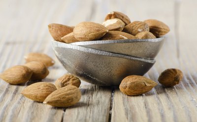 Almonds in a bowl on a wood table.