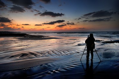 Photographer along shoreline at dusk
