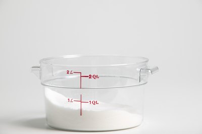 A measuring cup partially filled with cane sugar.