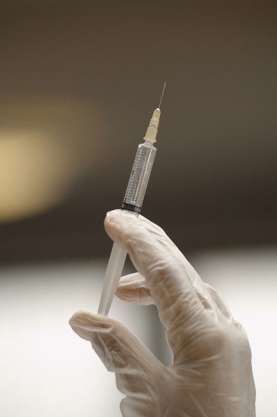 Gloved hand holding syringe
