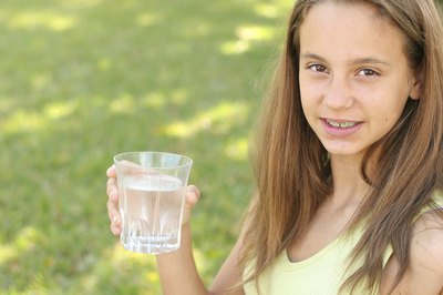 Girl with braces holding a glass of water