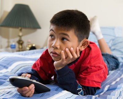 Boy watching television in bed