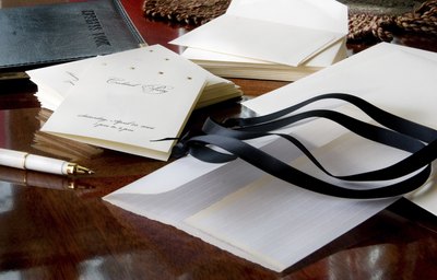 Paper invitations are sitting on a wooden desk.