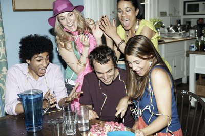 Man cutting birthday cake with friends