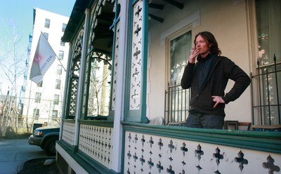Man smokes cigarette on hotel porch