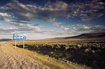 "Welcome to Idaho" sign alongside road.
