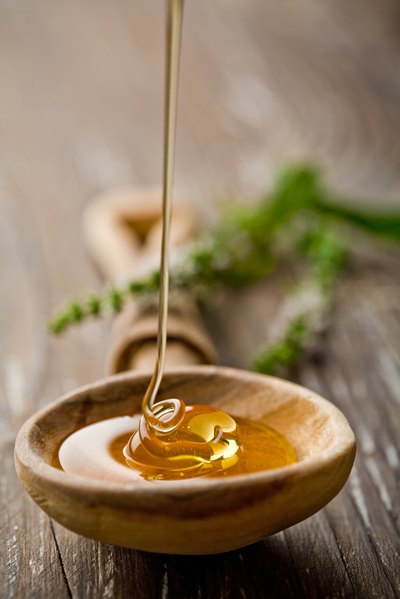 Honey dripping into wooden spoon