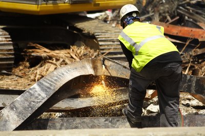 A worker cuts a steel beam at a demolition site.