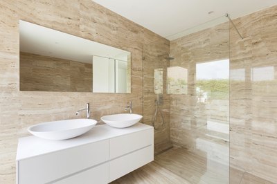 A modern bathroom shower with marble walls and floor.