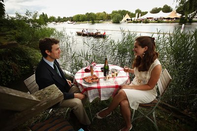 Couple enjoy champagne and smoked salmon lunch by the Henley-on-Thamas river in England
