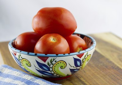 Roma tomatoes in a ceramic bowl on the table.