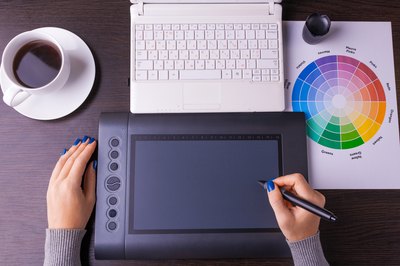 An overhead view of a designer working with a computer and color wheel at her desk