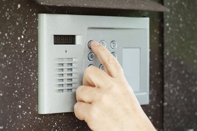 Fingers pushing buttons on an intercom system.