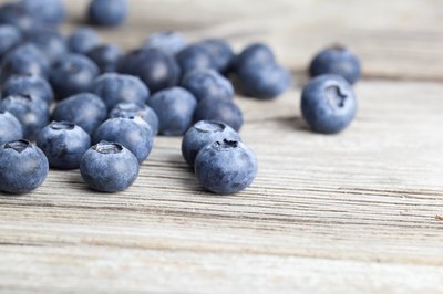 Fresh blueberries spilled onto a wood table.