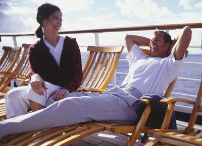 A couple sits on deck chairs on a cruise ship.