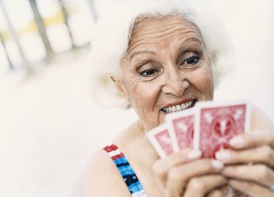 A mature woman holding playing cards.